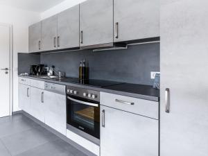 a kitchen with white cabinets and a black oven at limehome Montabaur Am Quendelberg in Montabaur