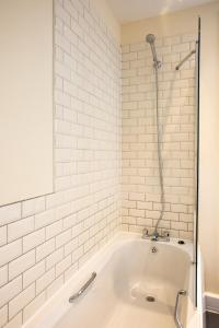 a white bath tub with a shower in a bathroom at Brewhouse and Kitchen in Bournemouth