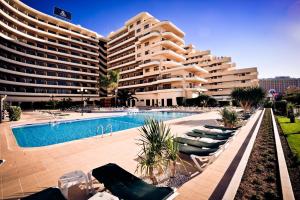 un grand immeuble avec piscine et chaises longues dans l'établissement Vila Gale Marina, à Vilamoura