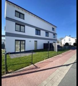 un bâtiment blanc avec une clôture devant lui dans l'établissement Luxusvilla Neubau 2, à Oberasbach