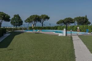 a swimming pool in a park with a green lawn at Mosaici Sunrise - lake front apartment with beautiful view in Sirmione