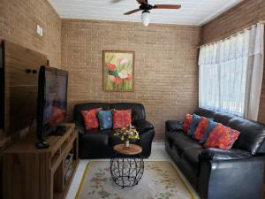 Meu lugar sana في سانا: غرفة معيشة مع أريكة جلدية سوداء وتلفزيون