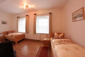 a bedroom with two beds and two windows at Pension Am Ostbahnhof in Gotha