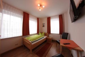 a bedroom with a bed and a desk and windows at Pension Am Ostbahnhof in Gotha