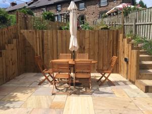 a wooden table with chairs and an umbrella on a patio at Birchwood Cottage - In the Heart of Wooler in Wooler