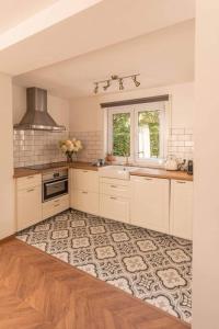 a kitchen with white cabinets and a sink and a window at Authentieke vakantiewoning op 200 m van het strand in De Panne