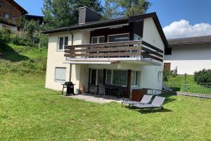 une maison blanche avec une terrasse et des chaises dans la cour dans l'établissement Haus Linaria - CharmingStay, à Flumserberg