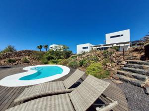 a swimming pool with two chairs and a house at Private villa with pool in Lajares in Lajares