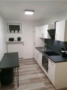 uma cozinha com armários brancos e um balcão preto em Haus Fasanerie em Fulda