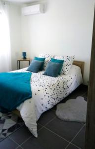 een bed met blauwe en witte lakens en kussens bij Le coin des Oliviers in Puget-sur Argens