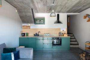 een keuken met blauwe kasten en een bank in een kamer bij Domek w górach - Prywatne Jacuzzi, Sauna, Grota Solna - PANORAMA CHEŁM SKI&SPA in Myślenice