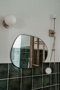 a mirror in a bathroom with green tiles at Rakstvežu apartamenti in Liepāja