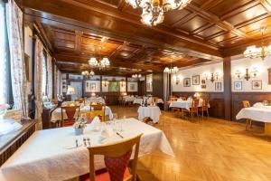 un ristorante con tavoli e sedie bianchi e soffitti in legno di Landgasthof Adler a Breisach am Rhein