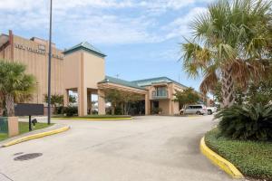 a large building with palm trees in a parking lot at Rodeway Inn & Suites in New Orleans