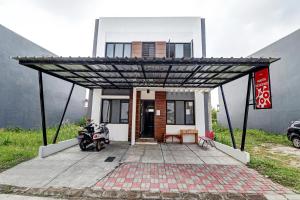 una casa con una motocicleta estacionada bajo una pérgola en OYO 90688 Marta Residence, en Karawang