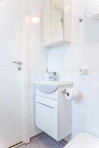 a white bathroom with a sink and a mirror at New Åkrahamn coast house in Sæveland