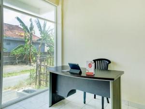 einen Schreibtisch mit einem Laptop und einem Stuhl vor einem Fenster in der Unterkunft OYO 90690 Pondok Dukuh in Ungasan