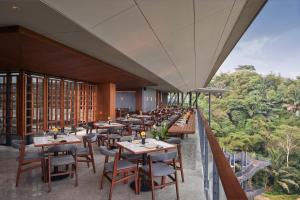 a restaurant with tables and chairs on a balcony at The Gaia Hotel Bandung in Bandung