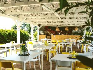 restauracja z białymi stołami i żółtymi krzesłami w obiekcie Hotel Magiczny Zakątek w mieście Raszowa