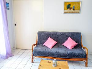 a blue couch with two pink pillows on a table at Apartment Parc de Pontaillac-10 by Interhome in Pontaillac