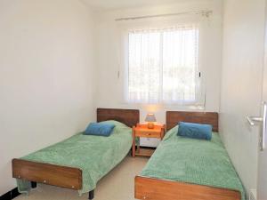 2 Betten in einem Zimmer mit einem Tisch und einem Fenster in der Unterkunft Apartment Corsaires 63 by Interhome in Saint Pierre La Mer