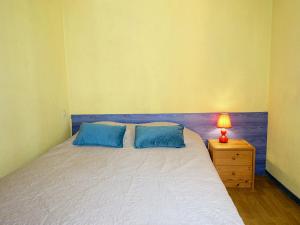 a bedroom with a bed with two blue pillows and a lamp at Apartment Les Balcons de la Méditerranée-18 by Interhome in Narbonne-Plage