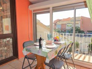 a table with chairs and a bottle of wine on a balcony at Apartment Les Balcons de la Méditerranée-18 by Interhome in Narbonne-Plage