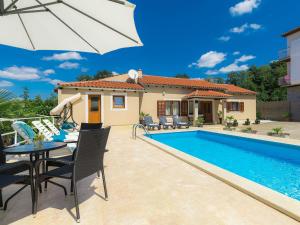 een villa met een zwembad en een tafel met een parasol bij Holiday Home Liberat by Interhome in Pazin