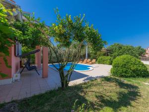 a garden with a swimming pool and a tree at Holiday Home Cherry - MDN149 by Interhome in Ližnjan