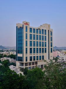 a tall white building with blue windows at Pride Hotel Udaipur in Udaipur