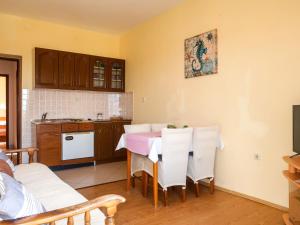 Apartment Andrija - RAB313 by Interhome في راب: مطبخ مع طاولة وردية وكراسي بيضاء