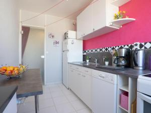 ニースにあるApartment Plein Soleil by Interhomeのピンクの壁のキッチン(白いキャビネット付)