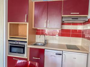 a kitchen with red cabinets and a sink at Apartment Les Rivages de Rochelongue-3 by Interhome in Cap d'Agde