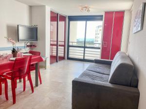 a living room with a couch and a red dining room table at Apartment Les Rivages de Rochelongue-3 by Interhome in Cap d'Agde