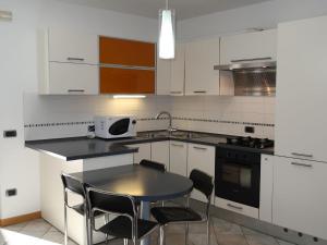 una cucina con armadi bianchi, tavolo e sedie di Apartment Schmid by Interhome a Caldonazzo