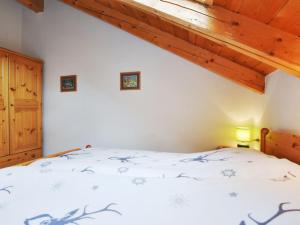 a bedroom with a bed with white sheets and wooden ceilings at Apartment Villa Placidia Apt 34 by Interhome in Campitello di Fassa +23 photos