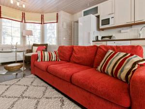 een rode bank in een woonkamer met een keuken bij Holiday Home Vuosselinhovi a by Interhome in Ruka