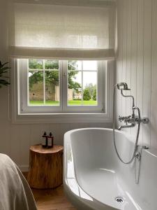 a white bath tub in a bathroom with a window at Ragnar Glamp Koknese in Koknese