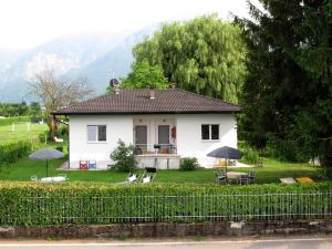 a white house with chairs and umbrellas in the yard at Holiday Home Villetta ai Pini-2 by Interhome in Calceranica al Lago