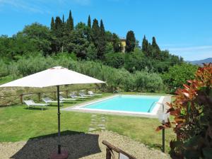 a swimming pool with an umbrella and chairs next to at Holiday Home Melograno by Interhome in Terranuova Bracciolini