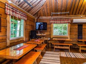Zimmer mit Holzwänden, Tischen und Fenstern in der Unterkunft Holiday Home Kuusenkatve by Interhome in Ruokonen