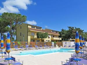 una piscina con ombrelloni e sedie blu e gialli di Apartment Riviera 5 by Interhome a Marina di Cecina