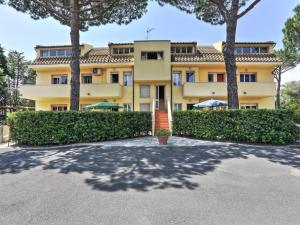 un grande edificio giallo con alberi di fronte di Apartment Riviera 1 by Interhome a Marina di Cecina