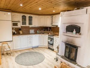 a kitchen with white cabinets and a fireplace at Holiday Home Suvantovirta by Interhome in Kaukonen