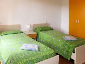 - 2 lits dans une chambre avec une couette verte dans l'établissement Apartment Riviera 2 by Interhome, à Marina di Cecina 23 autres photos