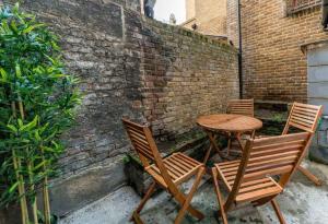 three chairs and a wooden table in front of a brick wall at Cozy 3 Bed Flat in the heart of Broadway Market in London