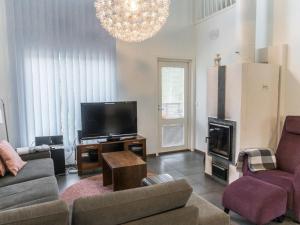 ein Wohnzimmer mit einem Sofa, einem TV und einem Kamin in der Unterkunft Holiday Home Vuokatinlampi 7 c by Interhome in Lahdenperä