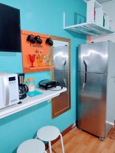 a kitchen with a refrigerator and a counter with stools at Pertinho prahia toninhas in Ubatuba