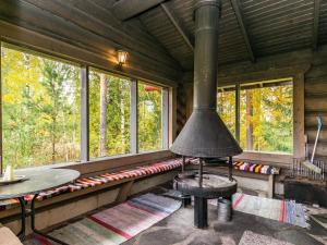 einen Kamin in einer Blockhütte mit einem Tisch und Fenstern in der Unterkunft Holiday Home Honkalinna by Interhome in Kokkosenlahti