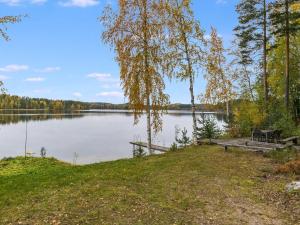 a picnic table and a bench on the shore of a lake at Holiday Home Honkalinna by Interhome in Kokkosenlahti
